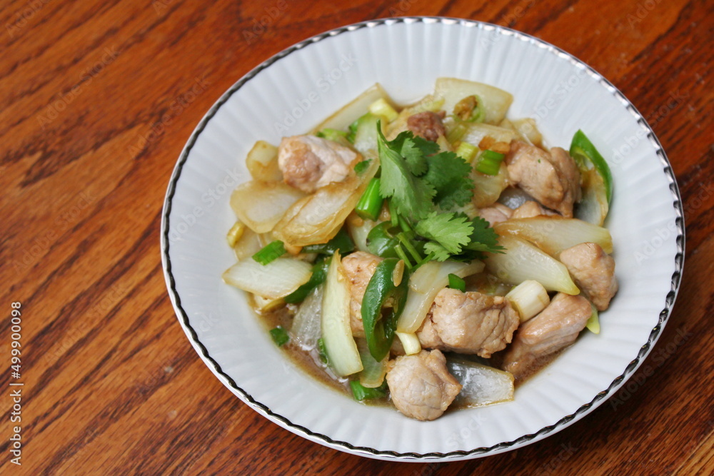 Stir-fried pork with chilli with onions and spring onions served in a white plate, Stir-fried pork with chilli is a popular Thai dish that Thai people eat. Stir-fried pork with chilli with onions and spring onions served in a white plate, Stir-fried pork with chilli is a popular Thai dish that Thai people eat.