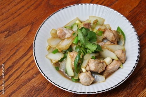 Stir-fried pork with chilli with onions and spring onions served in a white plate, Stir-fried pork with chilli is a popular Thai dish that Thai people eat.