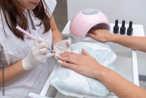 young woman in beauty center performing a nail service and beautification of hands and nails, by a beautician photo