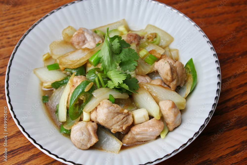 Stir-fried pork with chilli with onions and spring onions served in a white plate, Stir-fried pork with chilli is a popular Thai dish that Thai people eat.