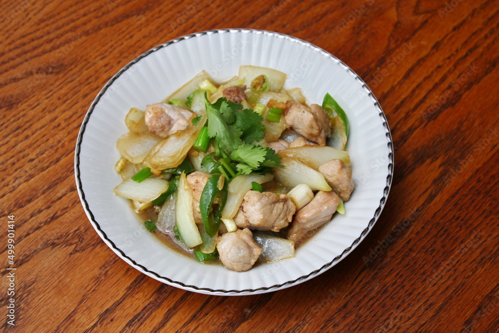 Stir-fried pork with chilli with onions and spring onions served in a white plate, Stir-fried pork with chilli is a popular Thai dish that Thai people eat. Stir-fried pork with chilli with onions and spring onions served in a white plate, Stir-fried pork with chilli is a popular Thai dish that Thai people eat.