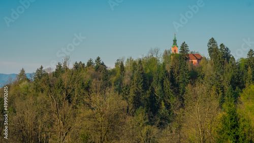 Panorama of Roznik hill with small red church hiding behind the trees in early morning sun. photo