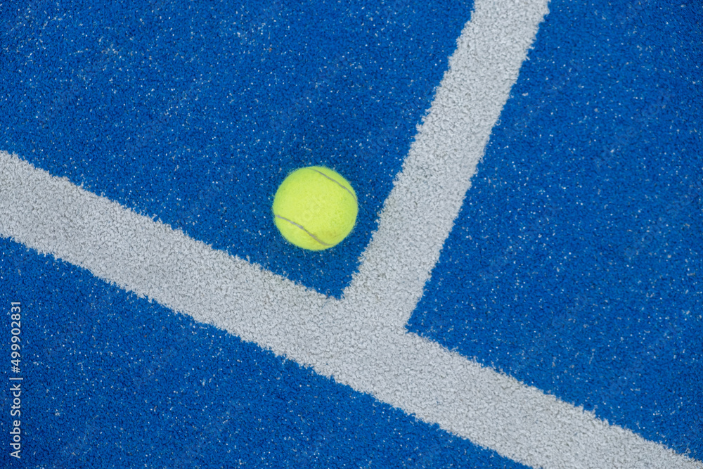 Tennis ball on a blue paddle tennis court