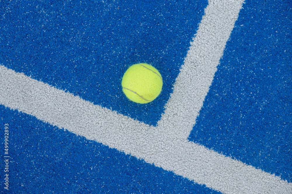 Tennis ball on a blue paddle tennis court, racket sports concept