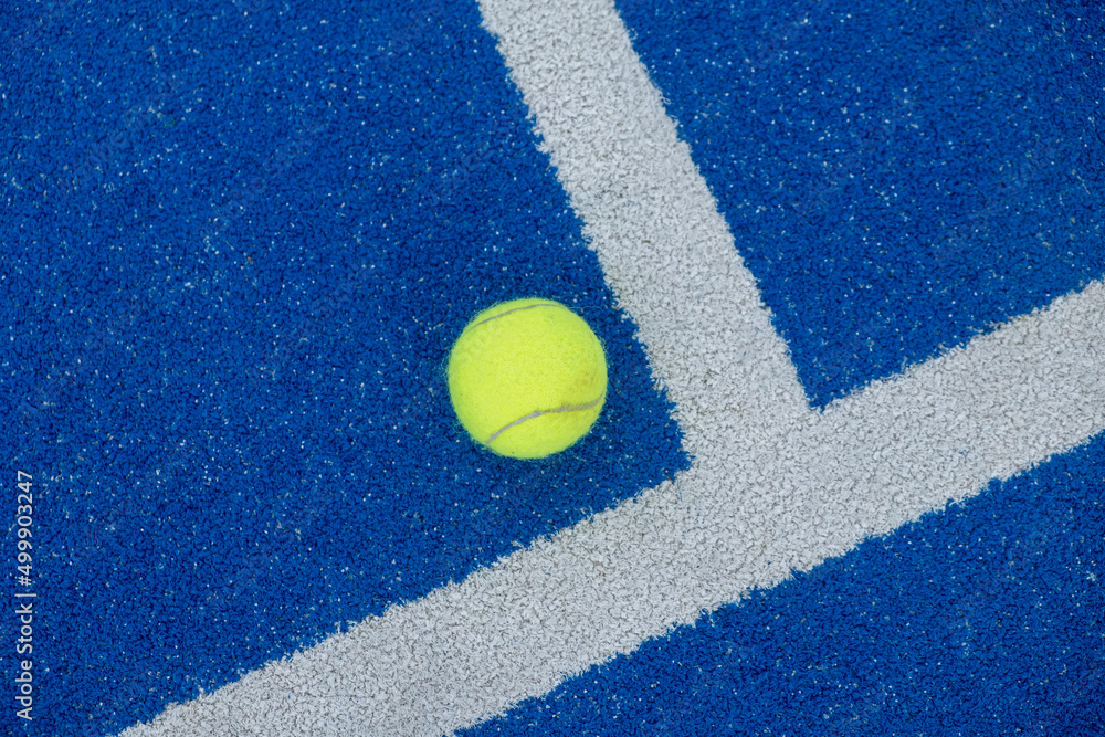 Tennis ball on a blue paddle tennis court, racket sports concept