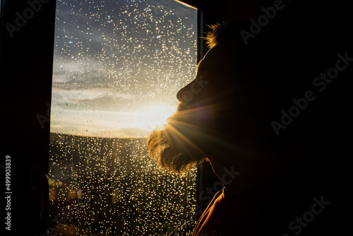 Fotografie, Obraz handsome adult man looking out on window on rainy day mental health