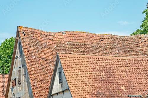 A closeup of red tile roofs, one that is sagging, on a dilapidated building hundreds of years old, Rothenberg, Germany.