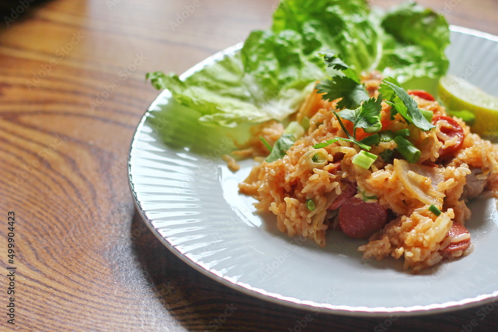 Pork and sausage fried rice served in a plate with lettuce and coriander garnish. Fried rice is a street food that is sold in Thailand. Pork and sausage fried rice served in a plate with lettuce and coriander garnish. Fried rice is a street food that is sold in Thailand.