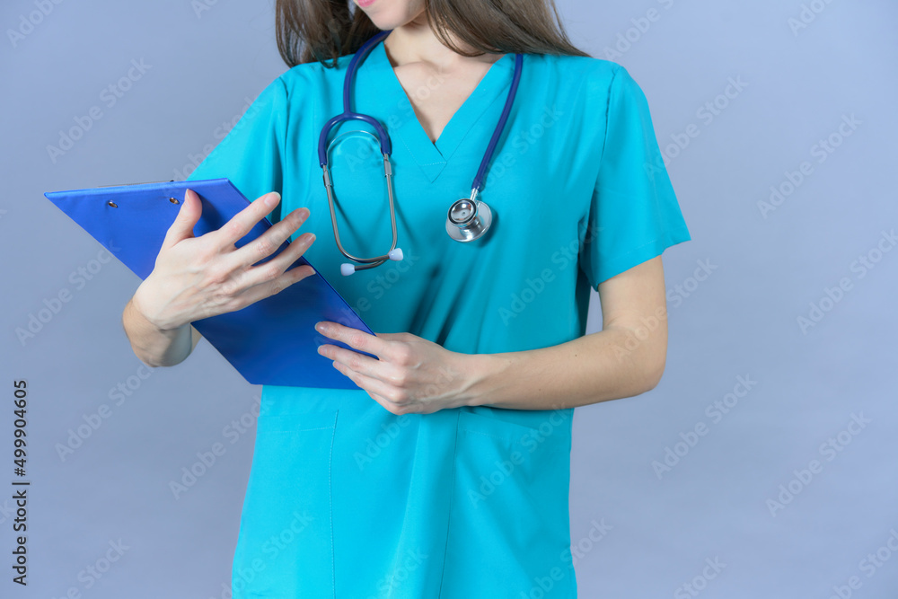 woman doctor nurse with stethoscope looking at blue paper clip with blue uniform on a blue background woman doctor nurse with stethoscope looking at blue paper clip with blue uniform on a blue background