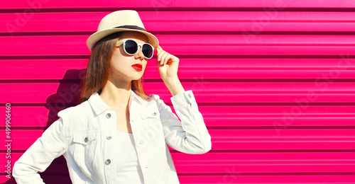 Portrait of beautiful young woman with red lipstick wearing summer straw hat, white shirt, sunglasses on pink background, blank copy space for advertising text