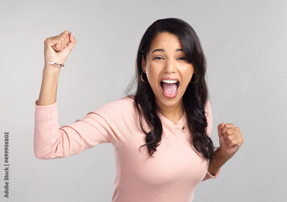 Were doing this. Shot of a beautiful young woman looking cheerful while standing against a grey background. Were doing this. Shot of a beautiful young woman looking cheerful while standing against a grey background.