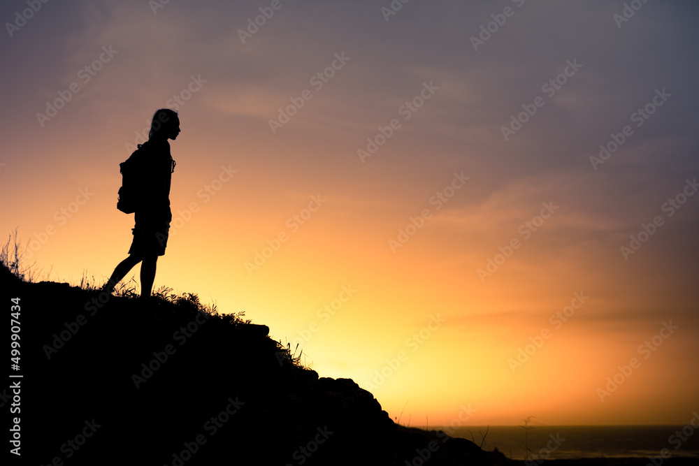 Silhouette of man on a mountain looking out to the horizon 