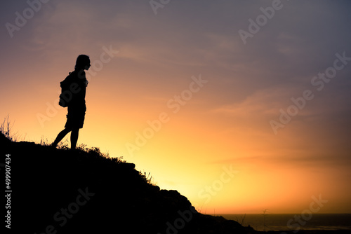 Silhouette of man on a mountain looking out to the horizon 