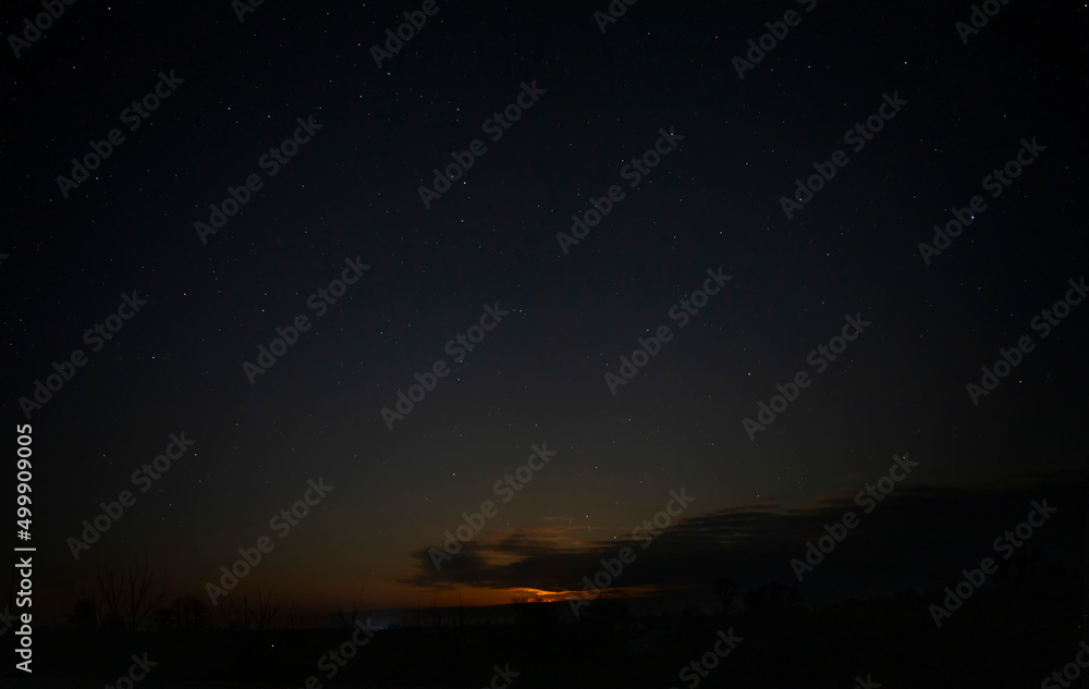 Fototapeta premium Orange night sky with stars and clouds.