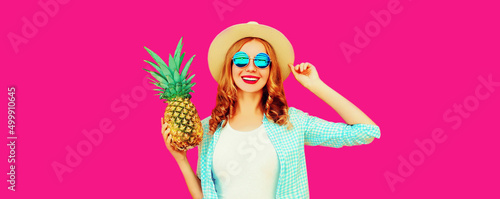 Summer portrait of happy smiling woman with pineapple wearing straw hat, sunglasses on pink background