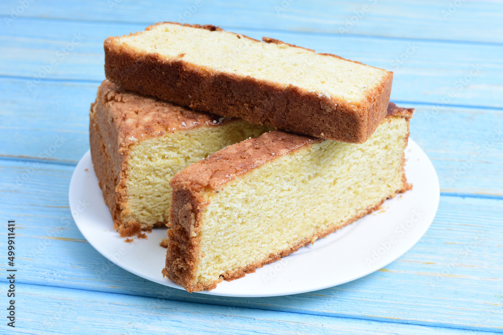 Homemade vanilla cake, displayed on a plate and portioned and on a wooden background