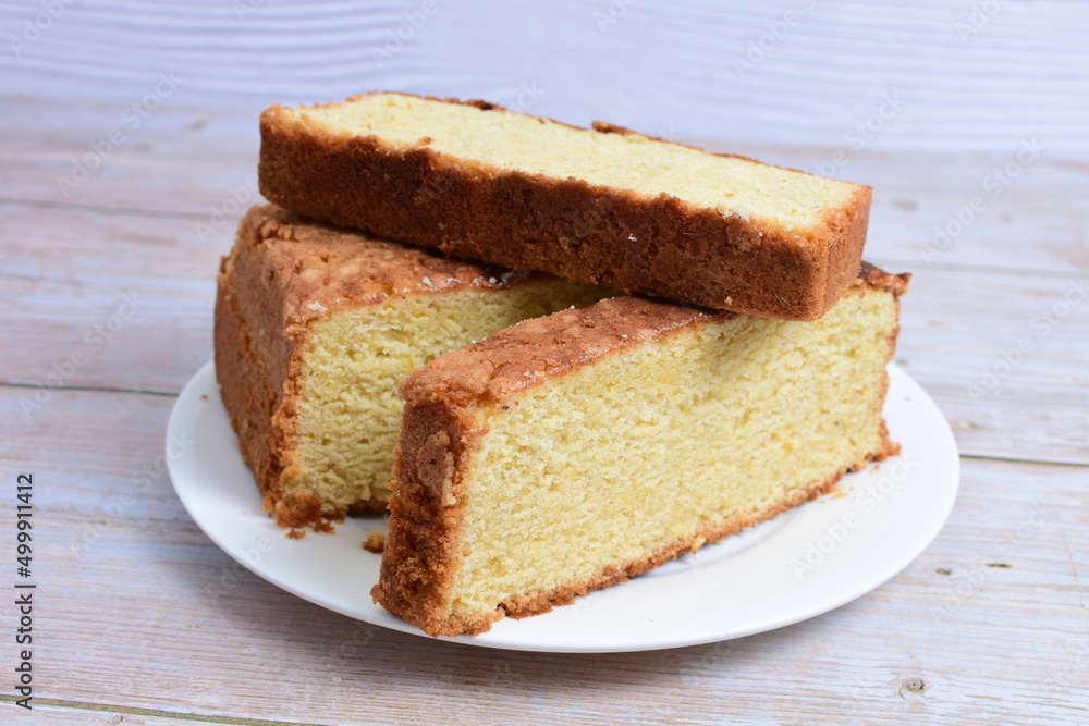 Homemade vanilla cake, displayed on a plate and portioned and on a wooden background Homemade vanilla cake, displayed on a plate and portioned and on a wooden background