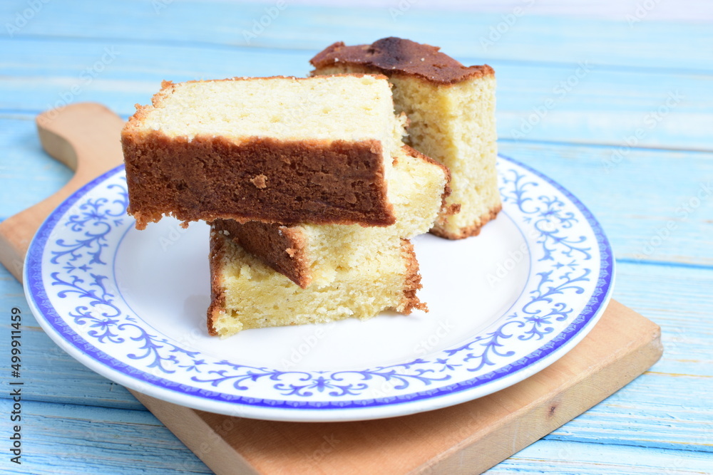 Homemade vanilla cake, displayed on a plate and portioned and on a wooden background Homemade vanilla cake, displayed on a plate and portioned and on a wooden background