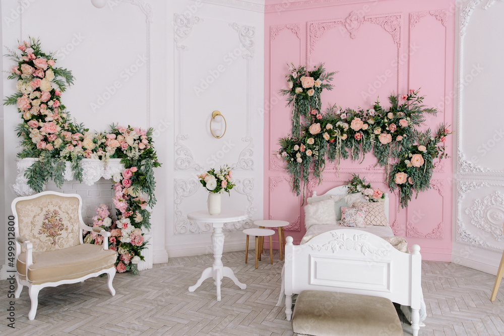 A children's room with a crib in white and pink, the walls are decorated with flowers. Modern design of the interior space in soft colors. The fireplace is decorated with flowers
