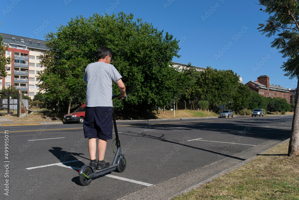 Hispanic senior man riding his electric kick scooter, modern transportation