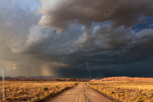 Fotografia Dirt road with dark, ominous storm clouds and lightning