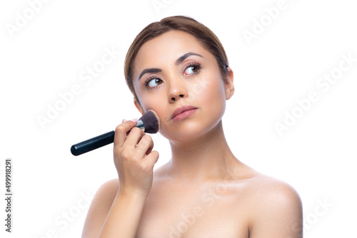 Close up portrait of a beautiful half naked woman with perfect, natural, clean and cosmetic skin and looking away. Hold makeup brush, make up in process. Isolated over white background.