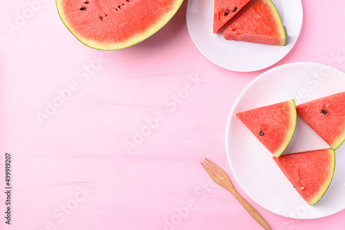 Sliced watermelon on plate with wooden fork on pink color background, Tropical fruit in summer season, Top view