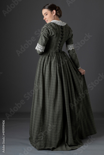 Foto A Victorian working class woman wearing a checked bodice and skirt and standing
