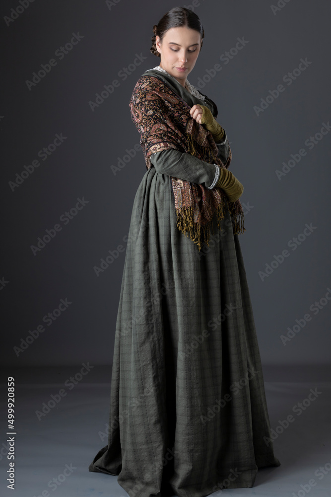 A Victorian working class woman wearing a green checked bodice and skirt with a lace collar and a paisley shawl