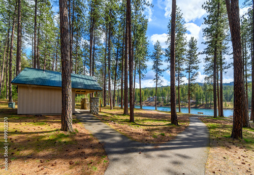 A small gazebo and hut alongside the path walkway leading to the Spokane River in the rural forested Kiwanis Park in Post Falls, Idaho, USA. photo