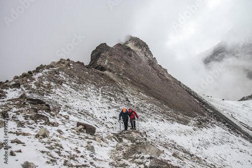 couple of mountaineers walking along a snow-filled route of the Iztaccihuatl - Popocatepetl National Park in Mexico photo