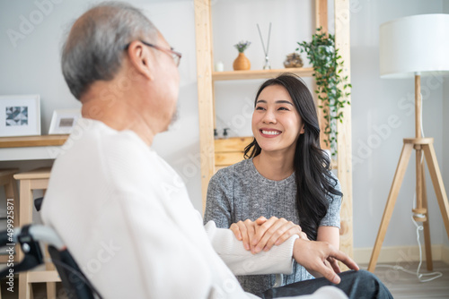Obraz na plátně Asian daughter support old disabled man sitting on wheelchair at home