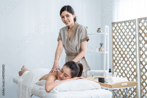Asian young relaxing woman getting back massage therapy with hot stone