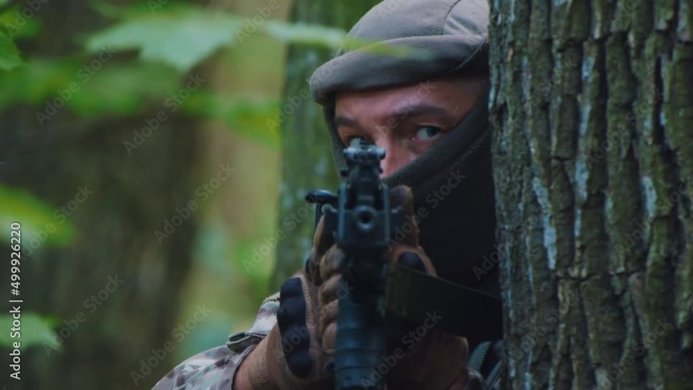 Man soldiers holding machine gun forward to attack enemy in forest. Machine gun barrel look at camera. Stand near tree in forest Man soldiers holding machine gun forward to attack enemy in forest. Machine gun barrel look at camera. Stand near tree in forest