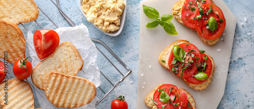 Tasty bruschettas with tomatoes, spices and hummus on color background