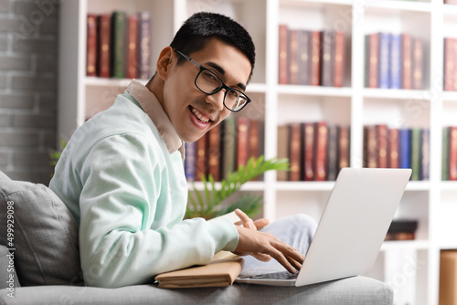 Male Asian student using la...