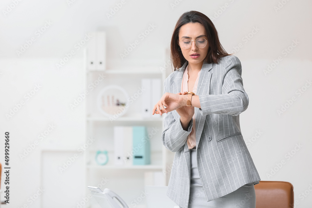 Portrait of young secretary looking at her watch in office Portrait of young secretary looking at her watch in office
