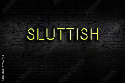Night view of neon sign on brick wall with inscription sluttish