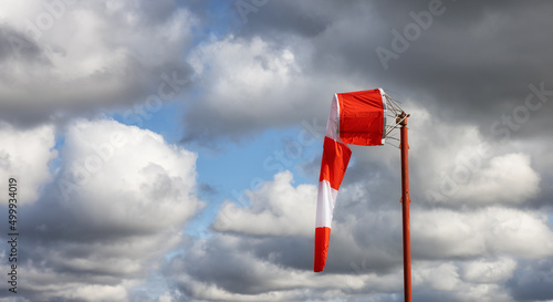 Windsock at an airport with a cloudy sunny sky in background. Light wind speed. photo