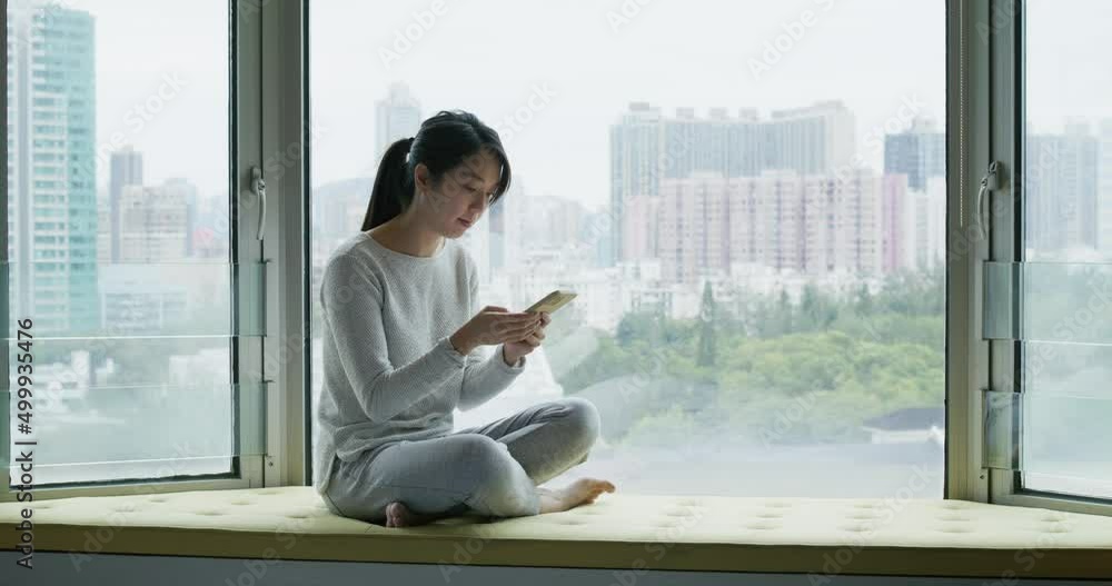 Woman use mobile phone and sit beside window Woman use mobile phone and sit beside window