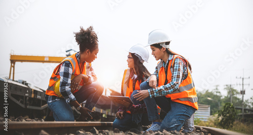 Team railway engineers are on duty and discussed by using tablet in the job site of train garage.