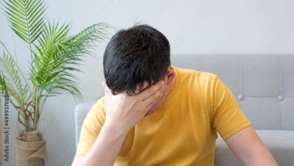 Man in yellow t-shirt covers his face with his hand, the concept of depression and stress. Man in yellow t-shirt covers his face with his hand, the concept of depression and stress.