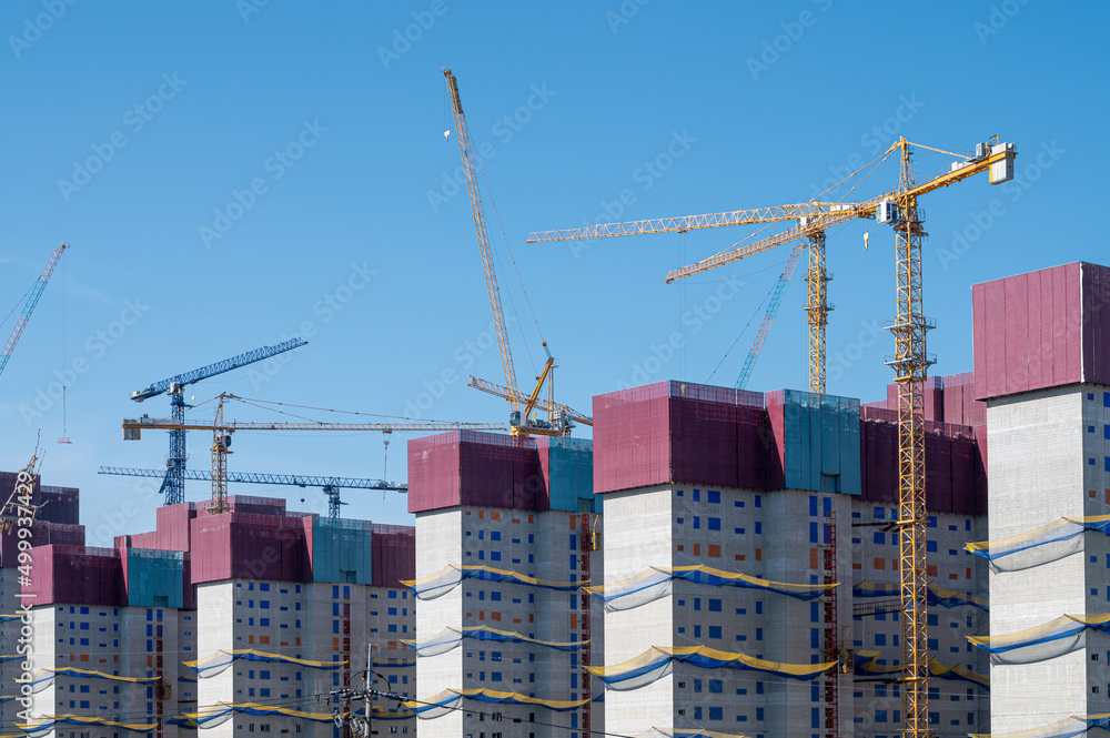 Panorama with many construction tower cranes in clear blue sky. Panorama with many construction tower cranes in clear blue sky.