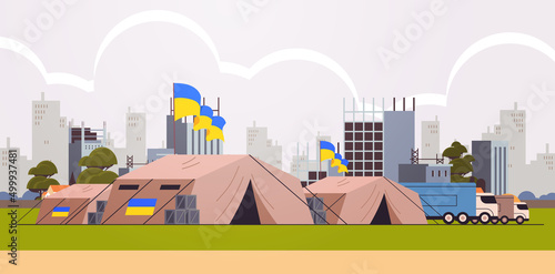 Humanitarian aid to refugees charity donation trucks and camp tents for sleep and volunteer the basic needs with Ukrainian flags