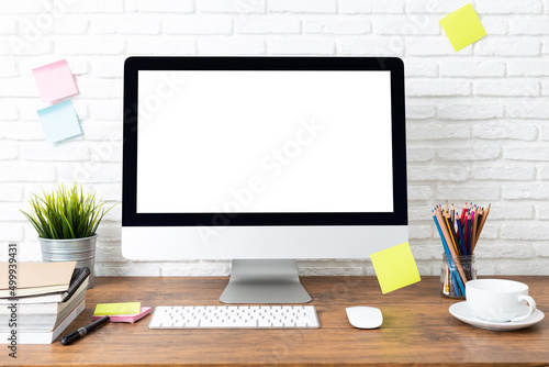 computer with blank white screen mockup, and office supplies on a wooden desk