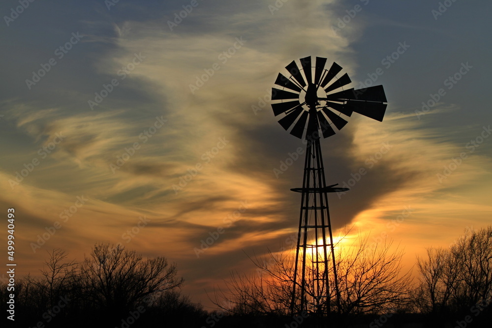 windmill at sunset with clouds and a colorful sky north of Hutchinson Kansas USA out in the country. windmill at sunset with clouds and a colorful sky north of Hutchinson Kansas USA out in the country.