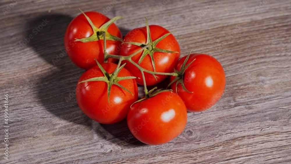 beautiful red tomatoes on a branch lie on a gray wooden table. top view beautiful red tomatoes on a branch lie on a gray wooden table. top view