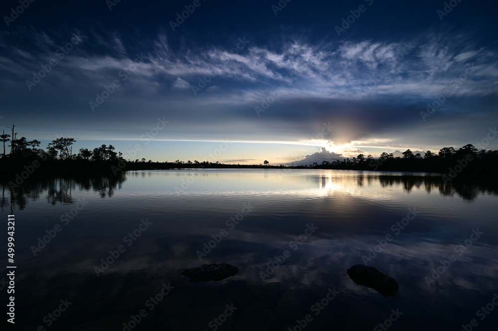 Beautiful sunset cloudscape over Pine Glades Lake in Everglades National Park, Florida reflected in lake's calm water.
