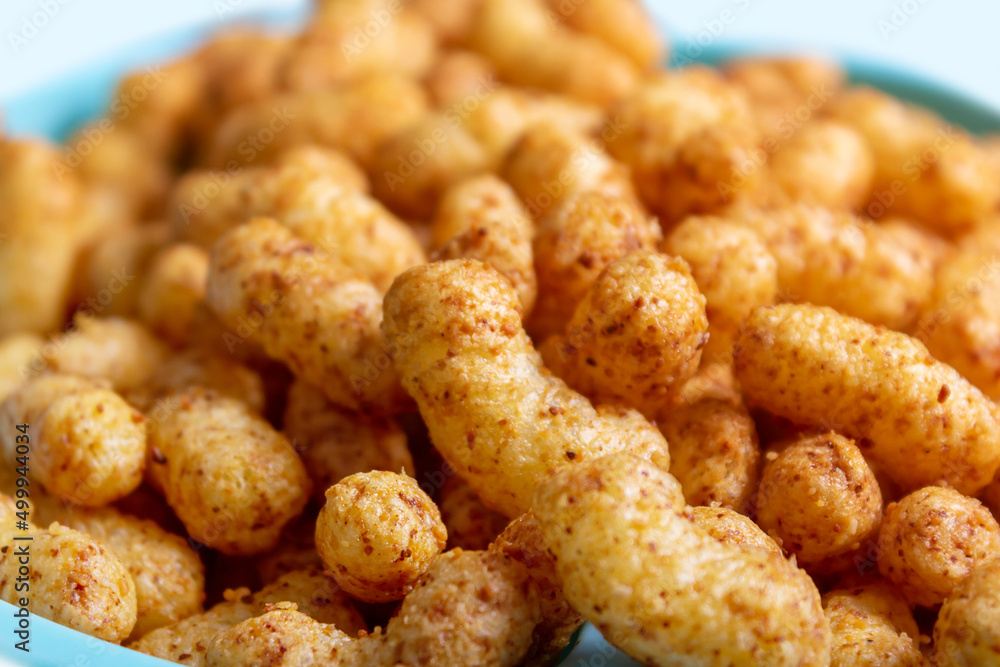 Puffed corn peanuts snacks on plate. Close-up. Puffed corn peanuts snacks on plate. Close-up.