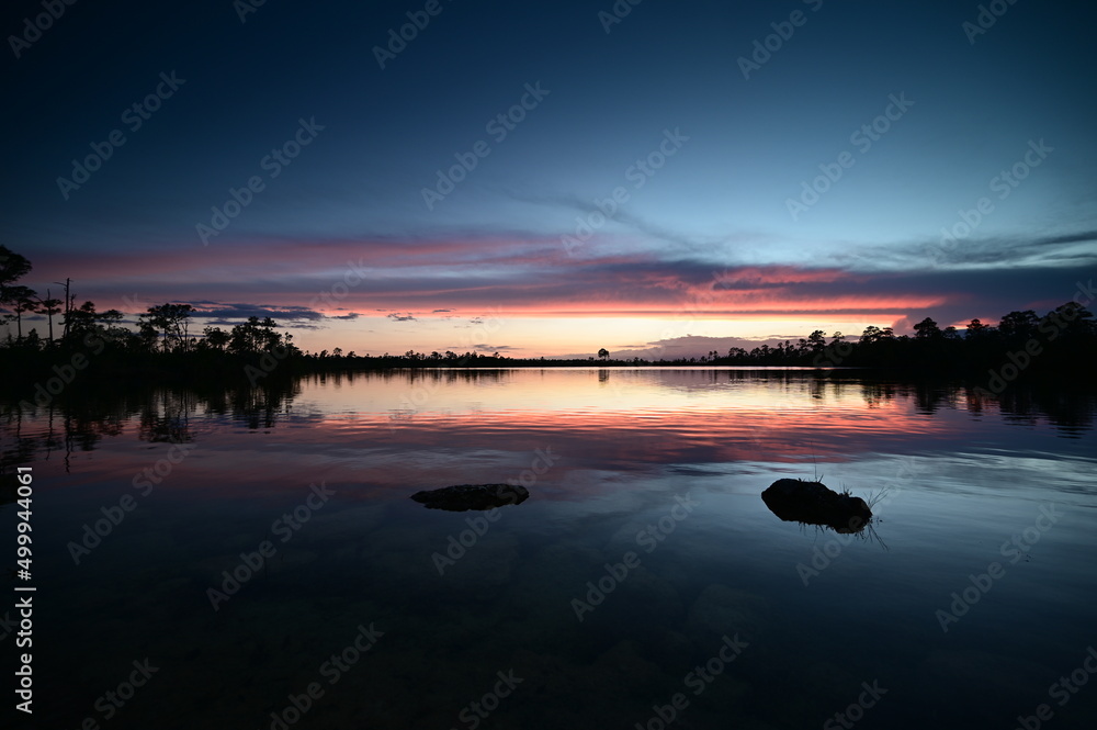 Beautiful sunset cloudscape over Pine Glades Lake in Everglades National Park, Florida reflected in lake's calm water.